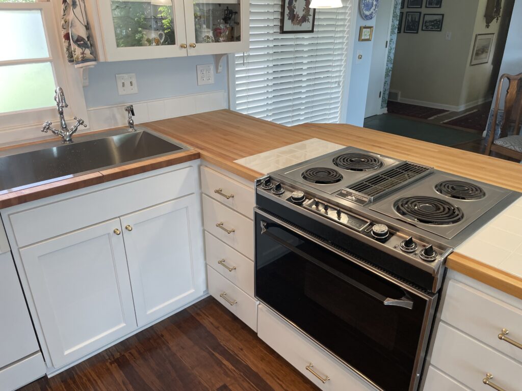 New single-bowl stainless steel sink and faucet set and existing drop-in Jenn-Air downdraft range with tile trivet inset into new Maple wood butcher block countertops by Action Craftworks LLC in Vancouver WA