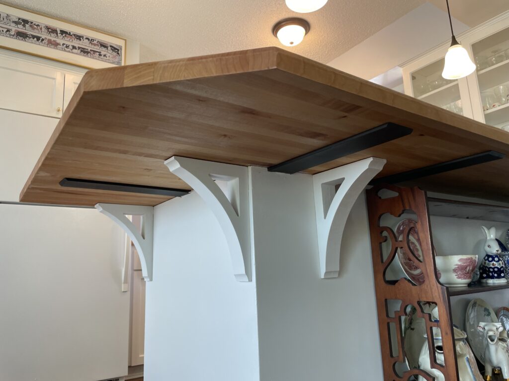 Heavy duty steel countertop supports and decorative painted wood corbels under butcher block countertop